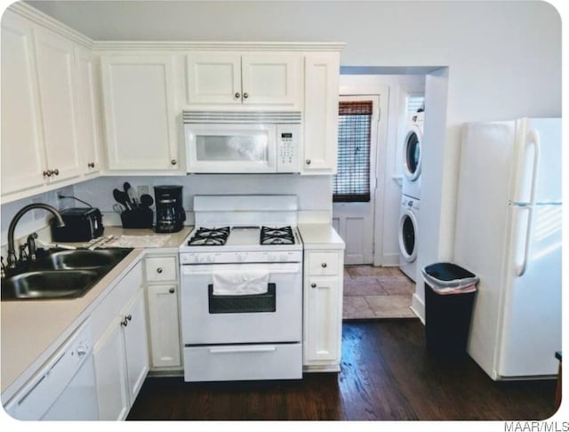 kitchen with white cabinetry, sink, white appliances, stacked washer / dryer, and dark wood-type flooring