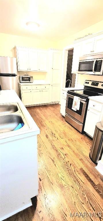 kitchen with white cabinets, light hardwood / wood-style flooring, stainless steel appliances, and sink