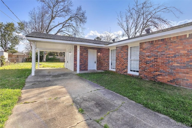 view of front of house with a front yard, fence, concrete driveway, a carport, and brick siding