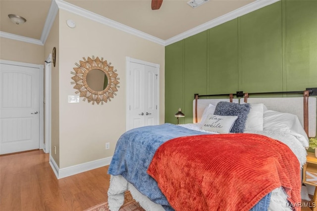 bedroom with ceiling fan, crown molding, wood-type flooring, and a closet