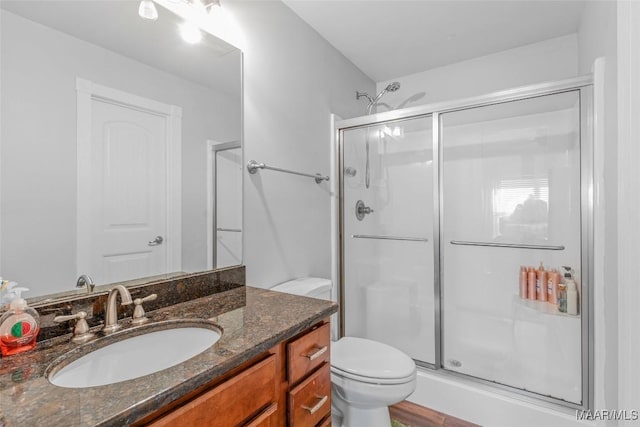 bathroom with vanity, toilet, and a shower with door