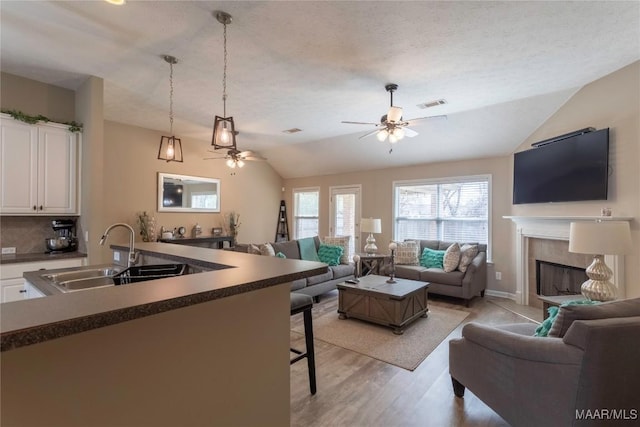 kitchen featuring white cabinetry, sink, a kitchen bar, and pendant lighting