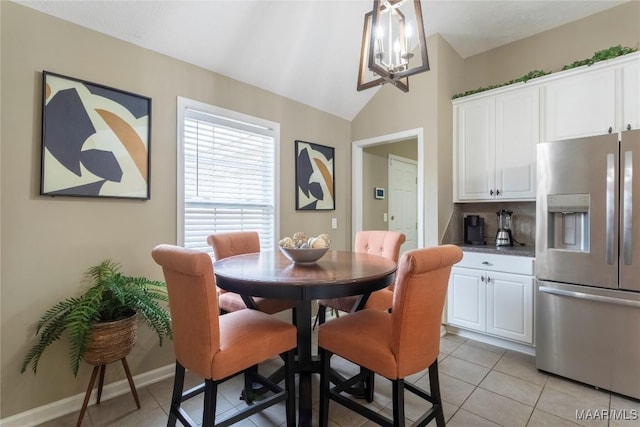 tiled dining room featuring vaulted ceiling and a notable chandelier