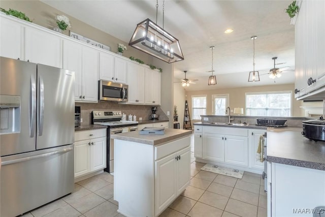 kitchen with white cabinetry, stainless steel appliances, a kitchen island, and sink