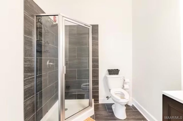 bathroom featuring vanity, toilet, and a shower with shower door