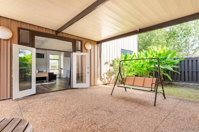 unfurnished sunroom featuring beam ceiling and french doors