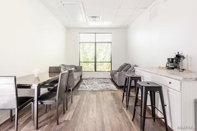 dining space featuring a paneled ceiling and hardwood / wood-style flooring