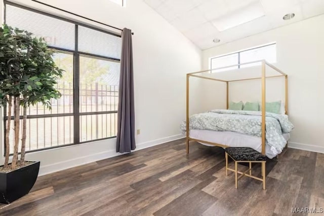 bedroom featuring dark wood-type flooring, vaulted ceiling, and multiple windows