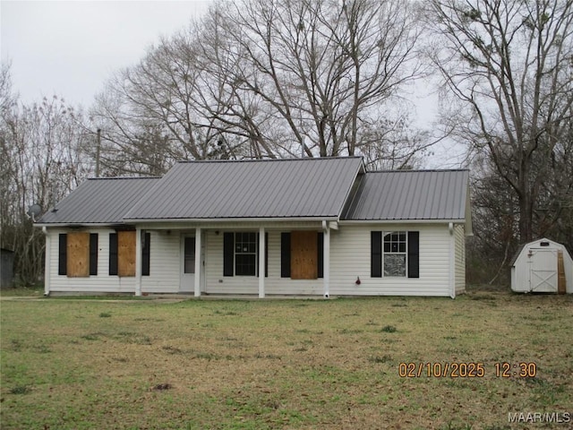 ranch-style home featuring metal roof, a shed, a front yard, and an outdoor structure