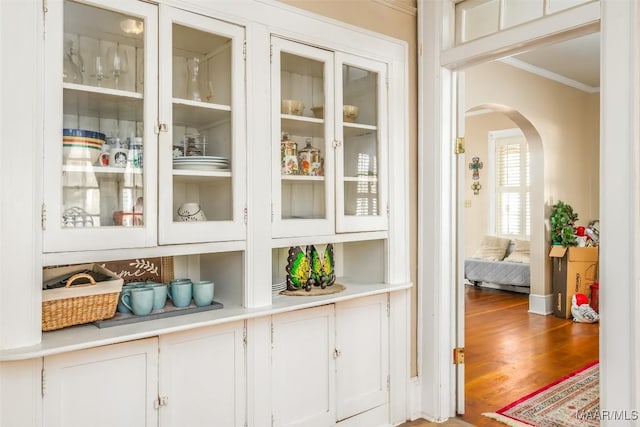 bar featuring light hardwood / wood-style floors, white cabinetry, and ornamental molding