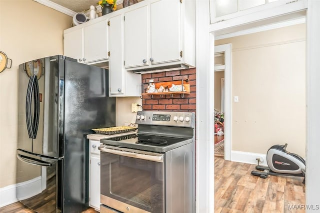 kitchen with black refrigerator, stainless steel range with electric stovetop, light hardwood / wood-style floors, ornamental molding, and white cabinetry