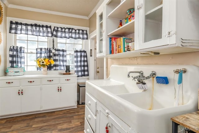 kitchen with dark hardwood / wood-style flooring, ornamental molding, sink, and white cabinets