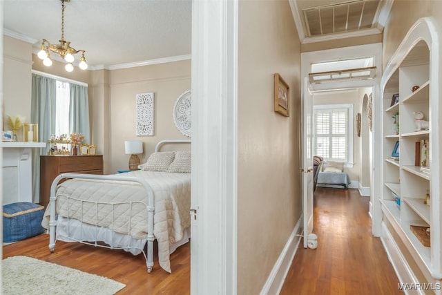 bedroom with crown molding, an inviting chandelier, and wood-type flooring