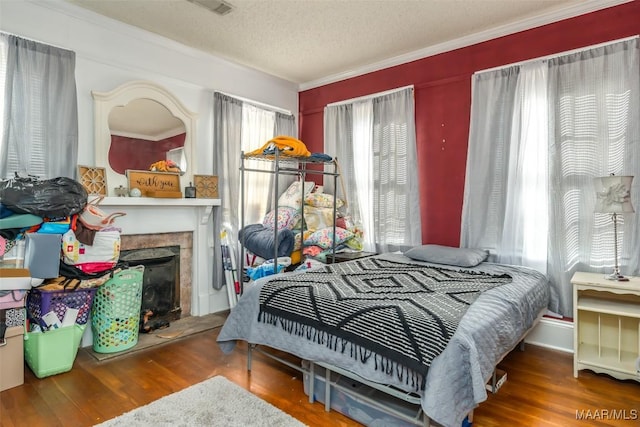 bedroom featuring a textured ceiling, ornamental molding, and wood-type flooring