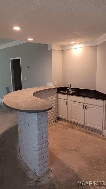 bar with white cabinetry, concrete flooring, sink, a textured ceiling, and crown molding