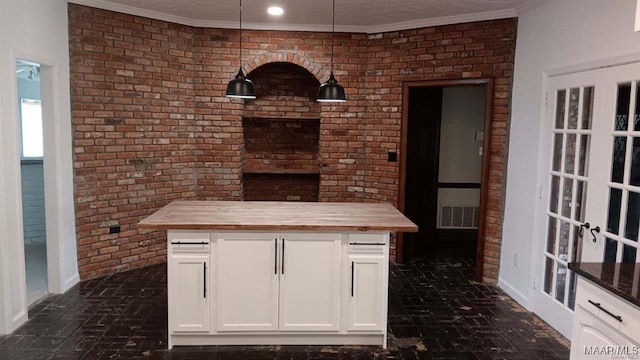 kitchen with white cabinetry, brick wall, butcher block countertops, and pendant lighting