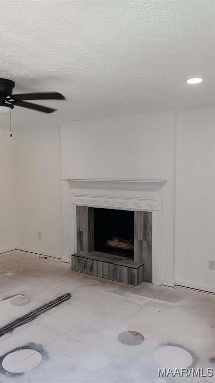 interior details featuring a fireplace, ceiling fan, and a textured ceiling