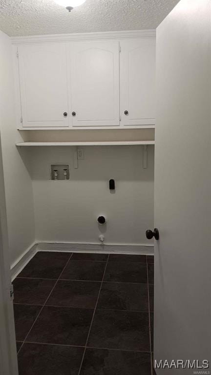 laundry area with cabinets, dark tile patterned floors, hookup for a washing machine, electric dryer hookup, and a textured ceiling