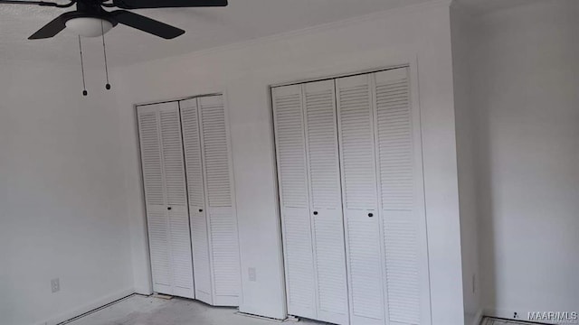 unfurnished bedroom with ceiling fan and two closets