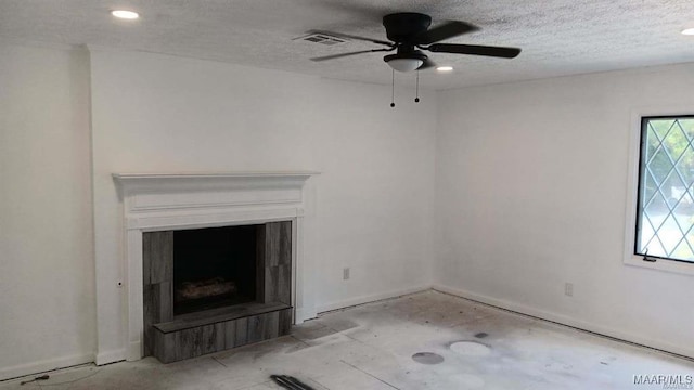 unfurnished living room featuring ceiling fan and a textured ceiling