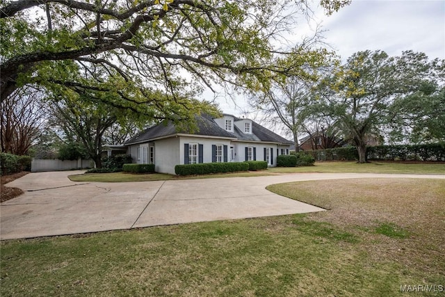 cape cod home featuring concrete driveway, fence, stucco siding, and a front yard