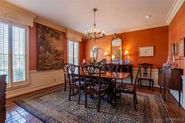 dining space with ornamental molding, wainscoting, wallpapered walls, and an inviting chandelier