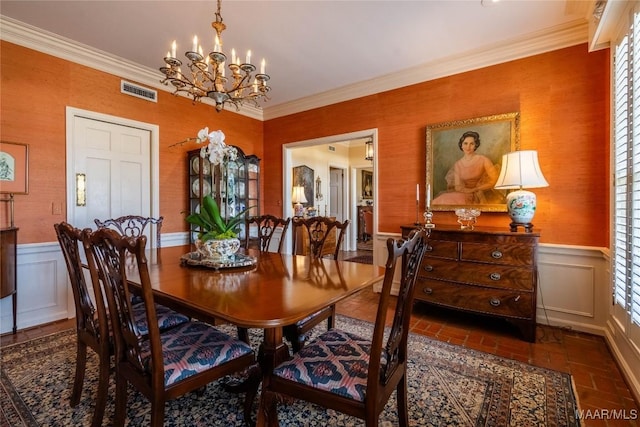 dining room featuring crown molding, wainscoting, visible vents, and brick floor