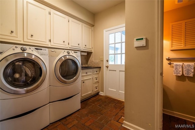 clothes washing area featuring brick floor, washer and dryer, baseboards, and cabinet space