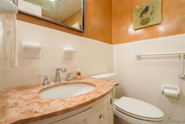 bathroom with vanity, tile walls, and toilet