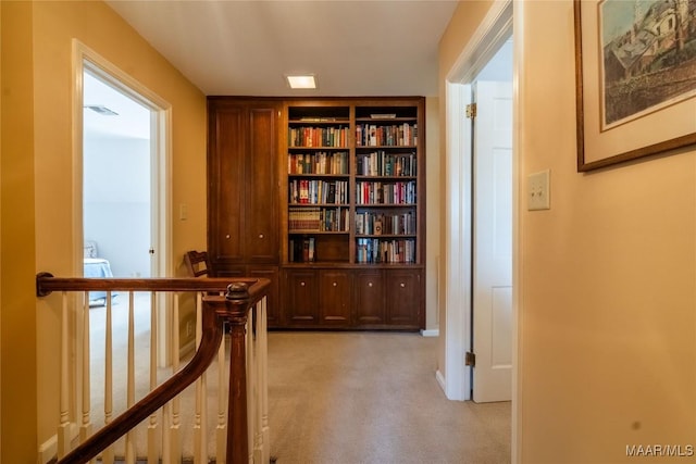 hallway with an upstairs landing and light carpet