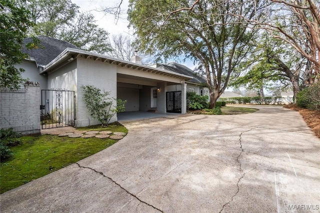 view of front facade with a carport, a chimney, and driveway