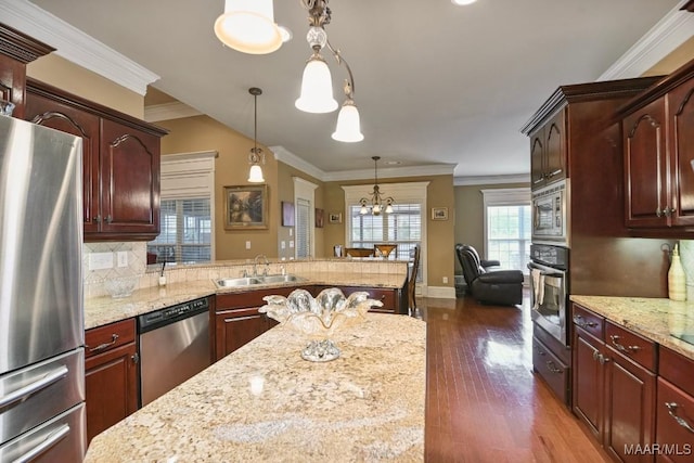 kitchen featuring stainless steel appliances, a sink, wood finished floors, a chandelier, and hanging light fixtures