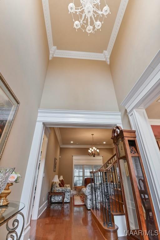foyer featuring a chandelier, stairs, crown molding, a high ceiling, and wood finished floors