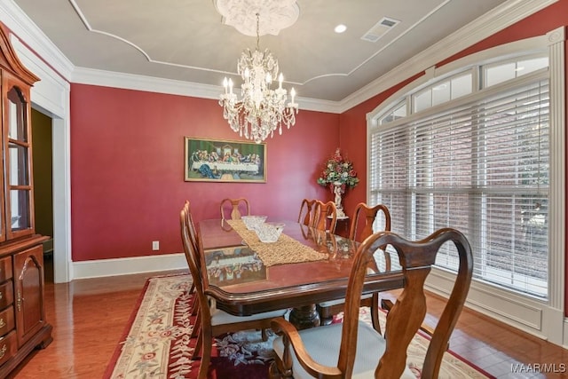 dining room featuring plenty of natural light, wood finished floors, crown molding, a chandelier, and baseboards