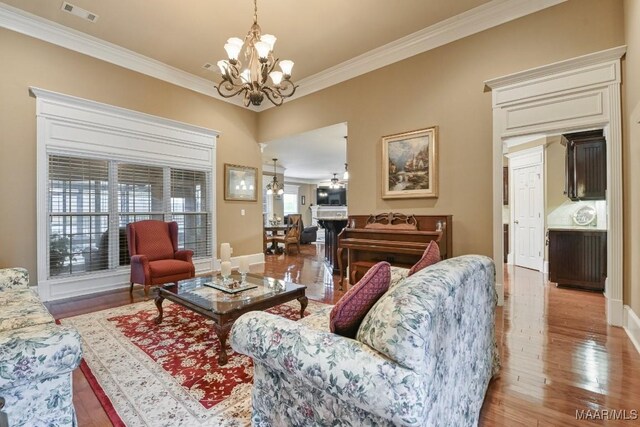living area featuring a chandelier, crown molding, wood finished floors, and baseboards