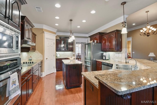kitchen featuring stainless steel appliances, a sink, a chandelier, crown molding, and tasteful backsplash