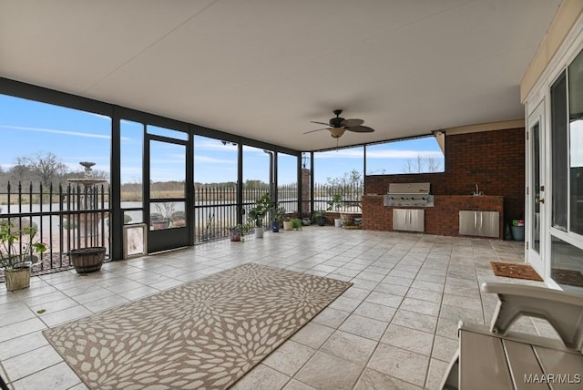 unfurnished sunroom with a water view, tile patterned flooring, brick wall, and a wall of windows