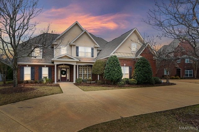 traditional-style home featuring brick siding and a shingled roof