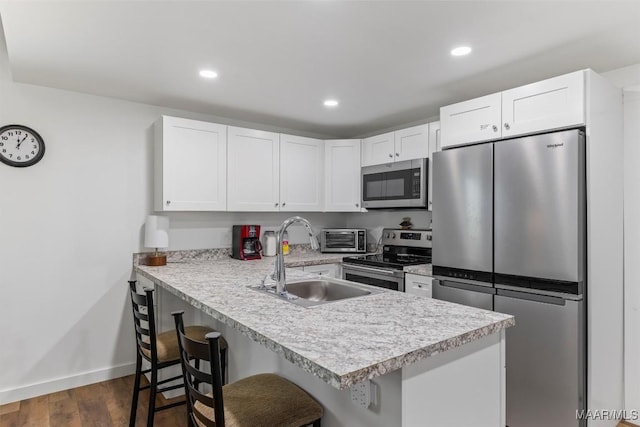 kitchen featuring a sink, stainless steel appliances, a peninsula, and light countertops