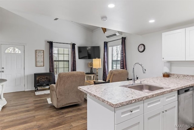 kitchen with a sink, white cabinets, open floor plan, light countertops, and stainless steel dishwasher