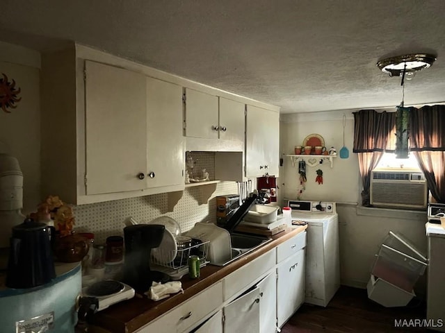 kitchen with dark countertops, washer / clothes dryer, white cabinets, and a textured ceiling