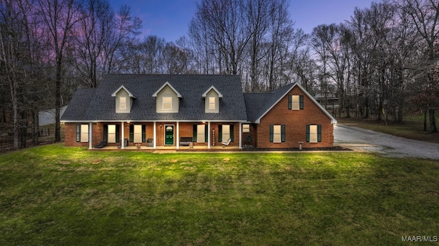 new england style home with a front lawn, a porch, and brick siding