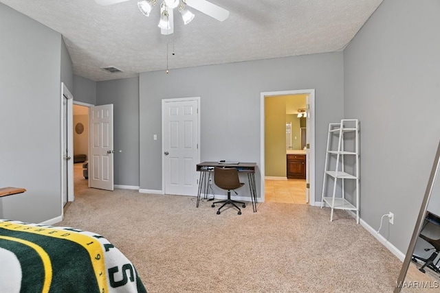 bedroom with light carpet, baseboards, a textured ceiling, and ensuite bathroom