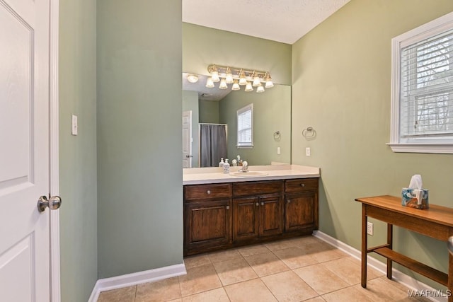 bathroom with tile patterned flooring, baseboards, and vanity