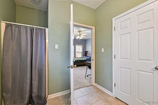 bathroom featuring a textured ceiling, connected bathroom, a ceiling fan, baseboards, and tile patterned floors