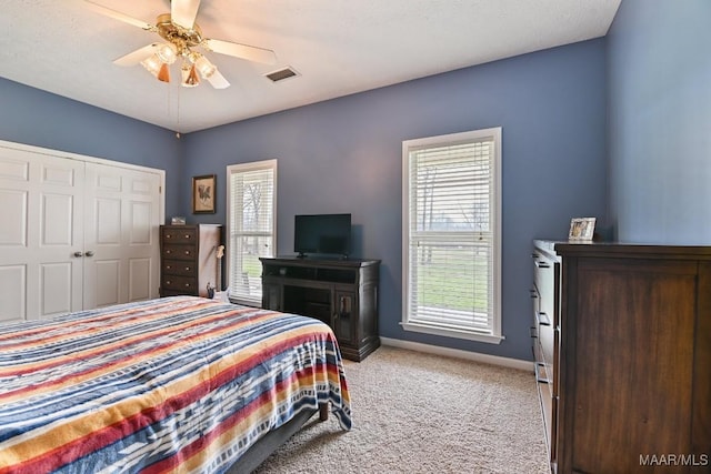 bedroom featuring light carpet, visible vents, baseboards, a ceiling fan, and a closet