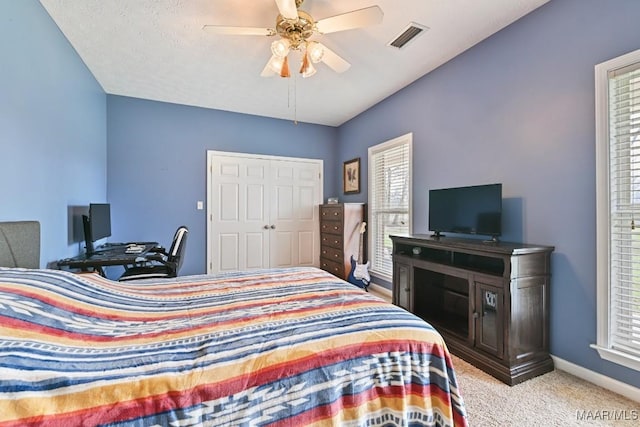 bedroom with baseboards, visible vents, light colored carpet, ceiling fan, and a closet