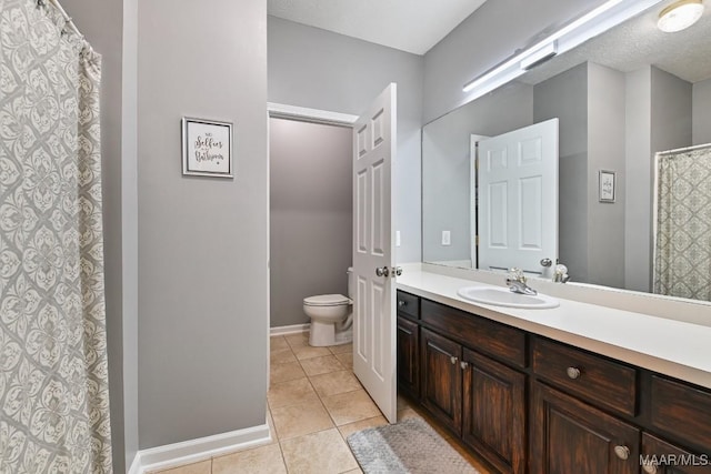 bathroom featuring toilet, tile patterned flooring, baseboards, and vanity