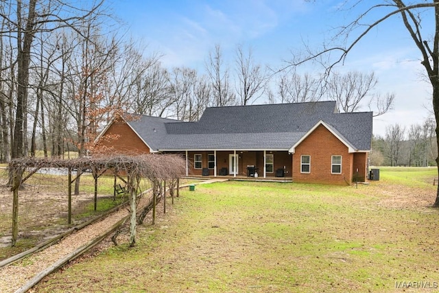 rear view of house featuring covered porch, brick siding, a yard, and central air condition unit