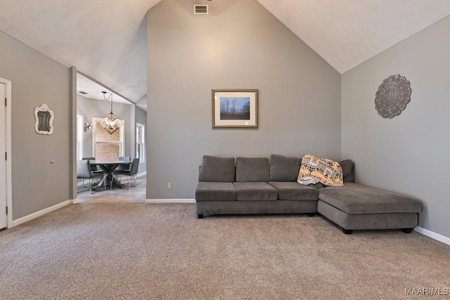 living area with baseboards, visible vents, light colored carpet, an inviting chandelier, and high vaulted ceiling